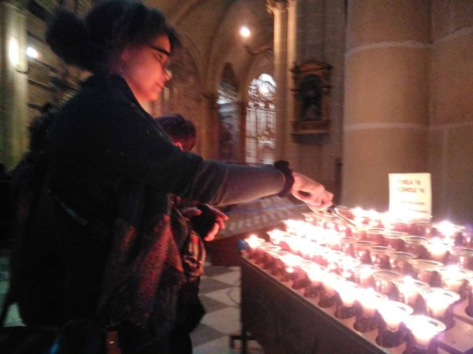 A woman lights a candle in a church.